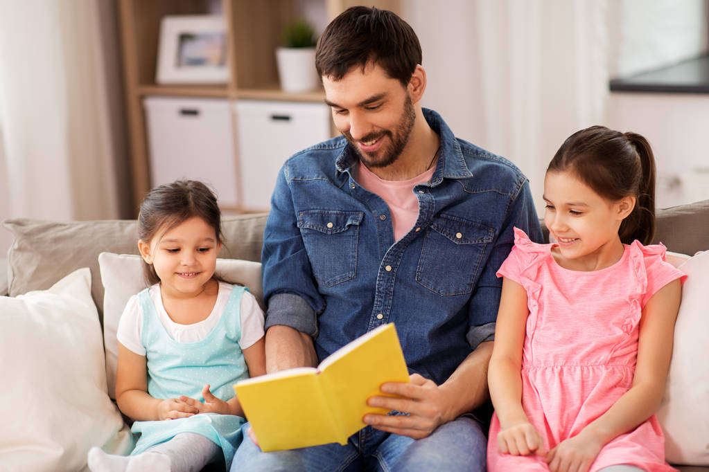 pai feliz com filhas lendo livro em casa
 - Foto, Imagem