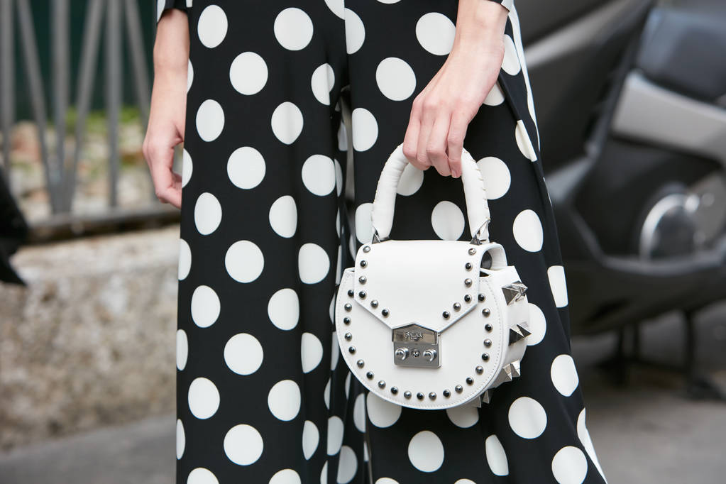 Mujer con bolso de cuero Salar blanco y vestido negro con puntos blancos antes del desfile de moda Antonio Marras, Milan Fashion Week street style on septiembre 23, 2017 in Milan
. - Foto, imagen