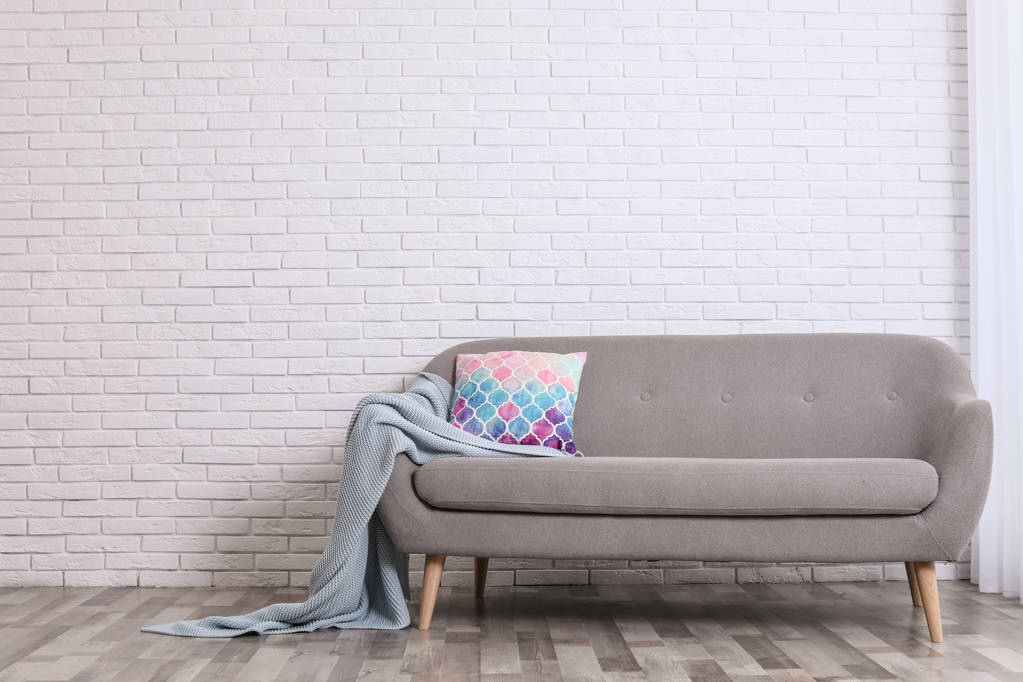 Minimalistinen olohuone sisustus kodikas sohva, tyyny ja ruudullinen lähellä tiiliseinää. Tekstitila
 - Valokuva, kuva