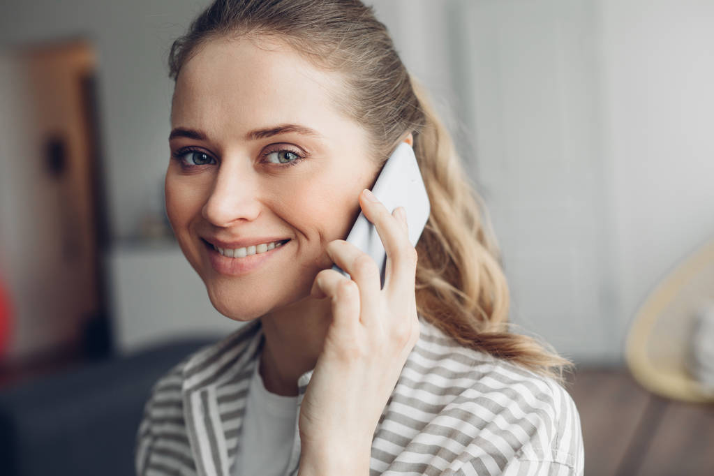 Молодая улыбающаяся женщина разговаривает по мобильному телефону
 - Фото, изображение