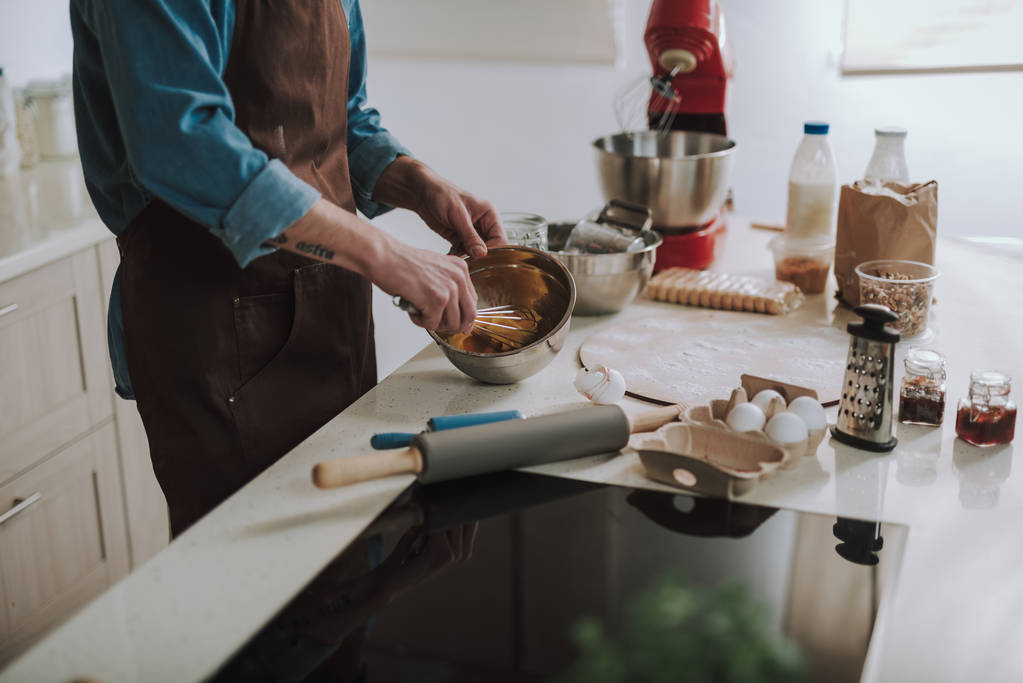Mesa de cocina con productos y persona batiendo huevos
 - Foto, Imagen