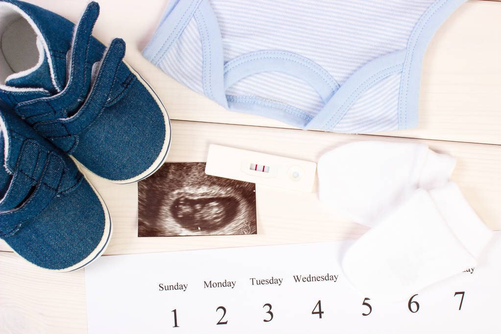 Teste de gravidez, ultra-som do bebê, roupas para recém-nascido e calendário, esperando para o conceito de bebê
 - Foto, Imagem