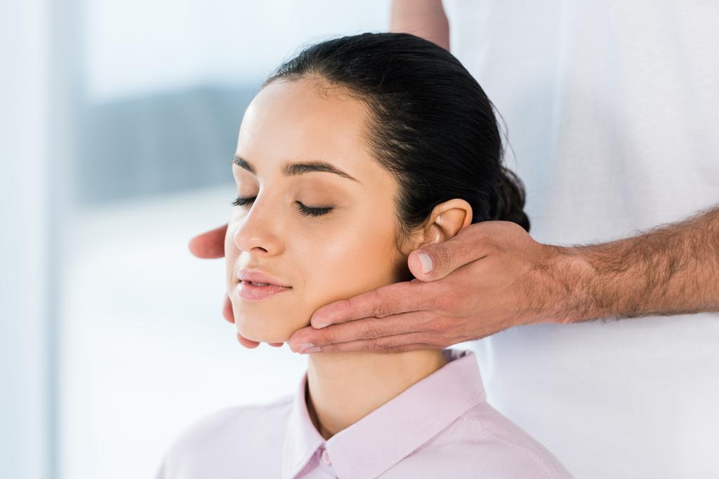 bijgesneden beeld van masseur handen vasthouden in de buurt van de nek van aantrekkelijke vrouw  - Foto, afbeelding