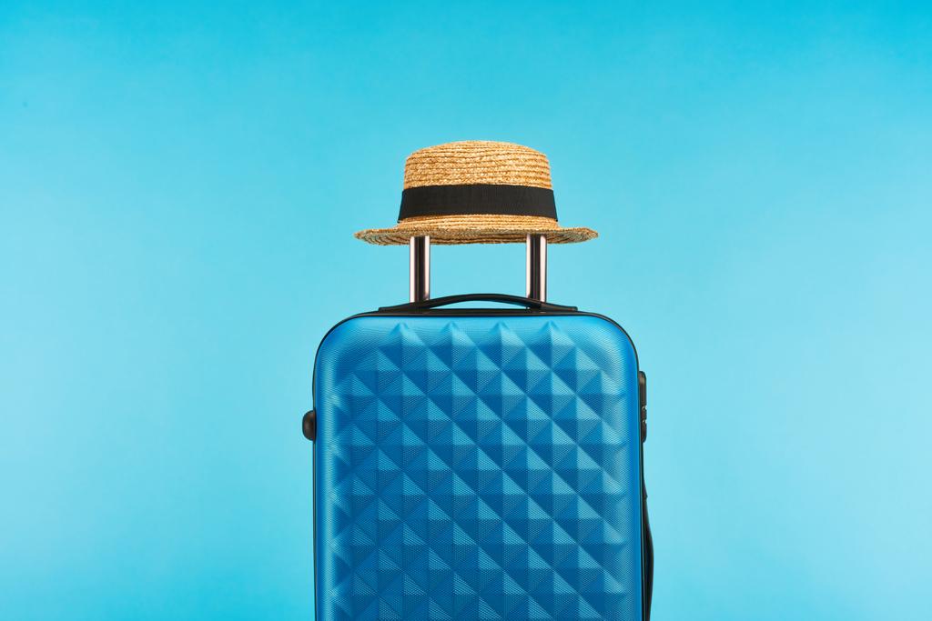 blaue bunte Reisetasche mit Griff auf Rädern auf blauem Hintergrund - Foto, Bild