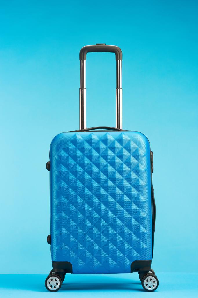 Niebieska torba podróżna z uchwytem na kółkach na niebieskim tle - Zdjęcie, obraz