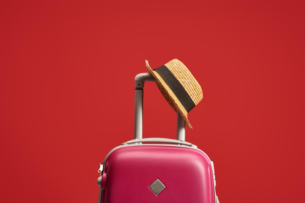 sac de voyage coloré avec chapeau de paille isolé sur rouge
  - Photo, image