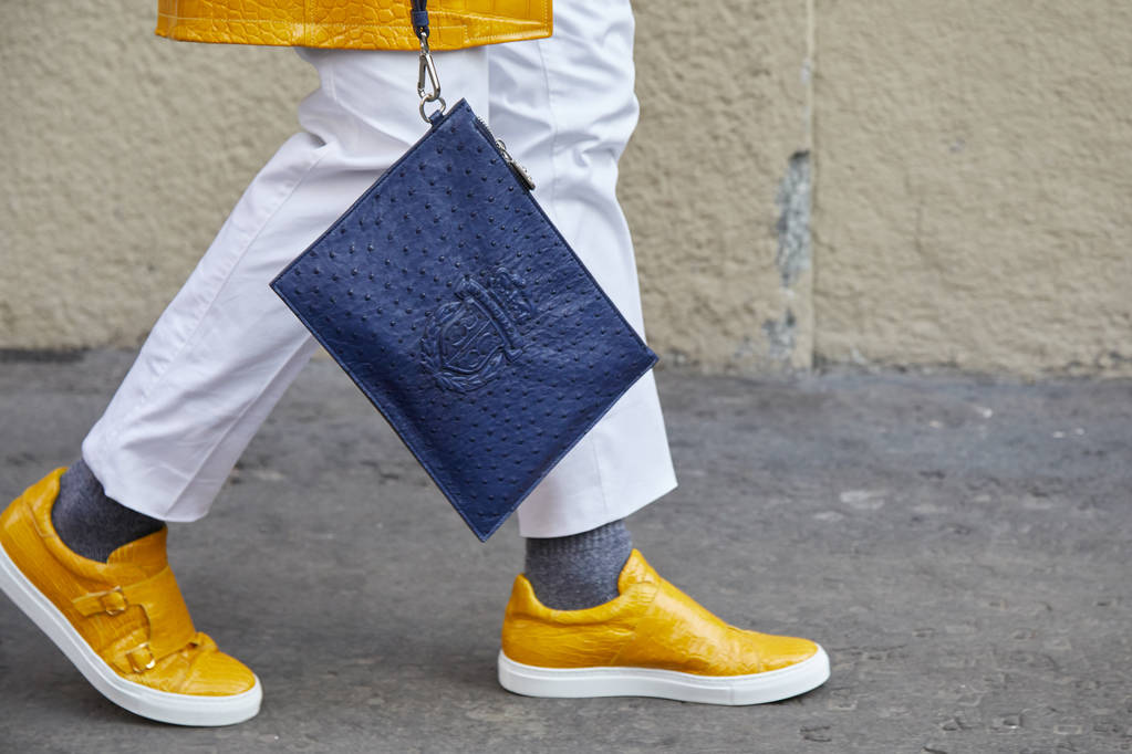 Hombre con zapatos de cuero amarillo caminando y bolso de piel de avestruz azul antes del desfile de moda Daks, Milan Fashion Week street style on enero 14, 2018 in Milan
. - Foto, imagen