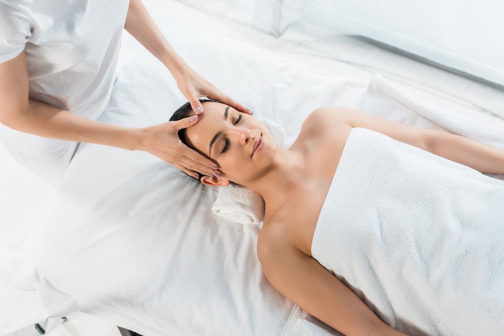 vue aérienne de masseur faisant massage de la tête à jolie femme sur table de massage
  - Photo, image