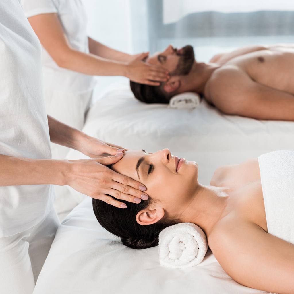 vue recadrée de masseurs faisant massage à la femme et l'homme dans le centre de spa
  - Photo, image