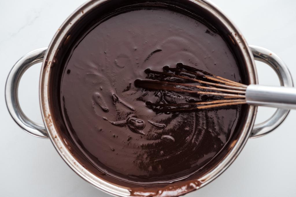 Вид зверху на сковороду з розтопленим темним шоколадом і повітряним віночком
  - Фото, зображення