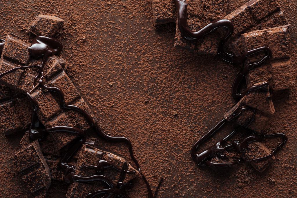 Vista superior de trozos de chocolate con chocolate líquido y cacao en polvo sobre fondo metálico
 - Foto, imagen