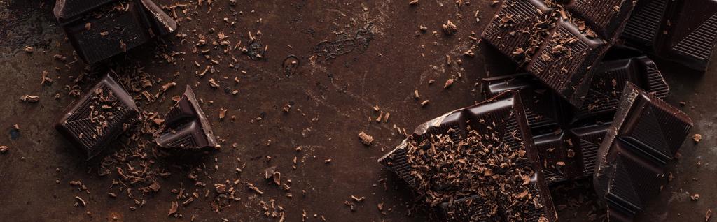 Panoramaaufnahme eines Schokoriegels mit Schokoladenstücken auf Metallhintergrund  - Foto, Bild