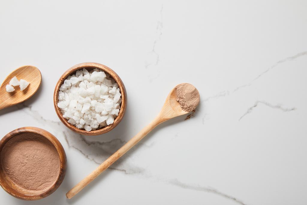 pohled na hliněný prášek a mořskou sůl v miskách na mramorovém stole blízko dřevěných Spoonů - Fotografie, Obrázek