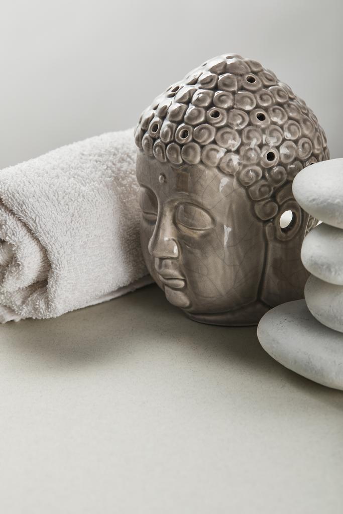 бавовняний рушник, камені, статуетка Будди на білому столі ізольовані на сірому
 - Фото, зображення