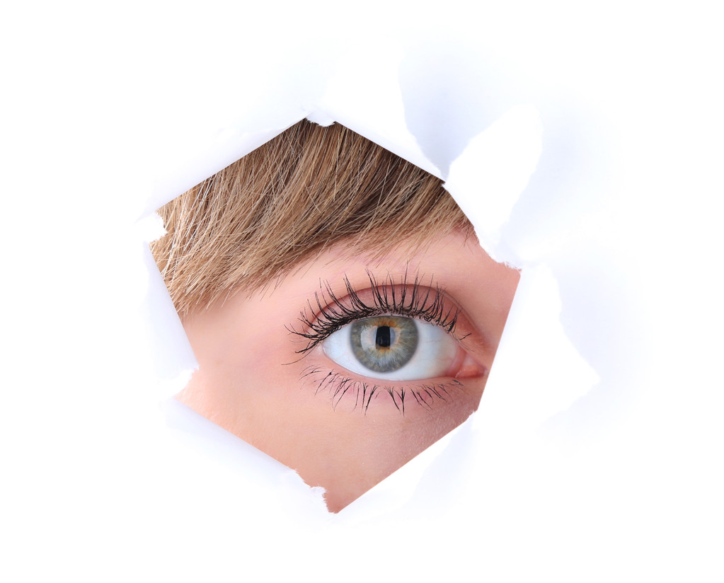Γυναικεία μάτια αναζητούν μέσα από την τρύπα στο φύλλο χαρτιού - Φωτογραφία, εικόνα