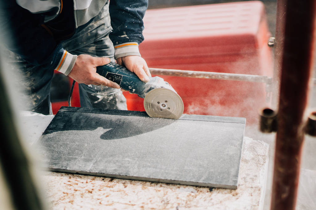Details van werknemer snijden steen marmer met haakse slijper op bouwplaats - Foto, afbeelding