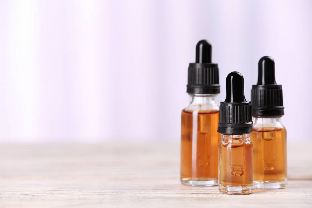 Bottles of essential oils on table against light background, space for text. Cosmetic products - Photo, Image