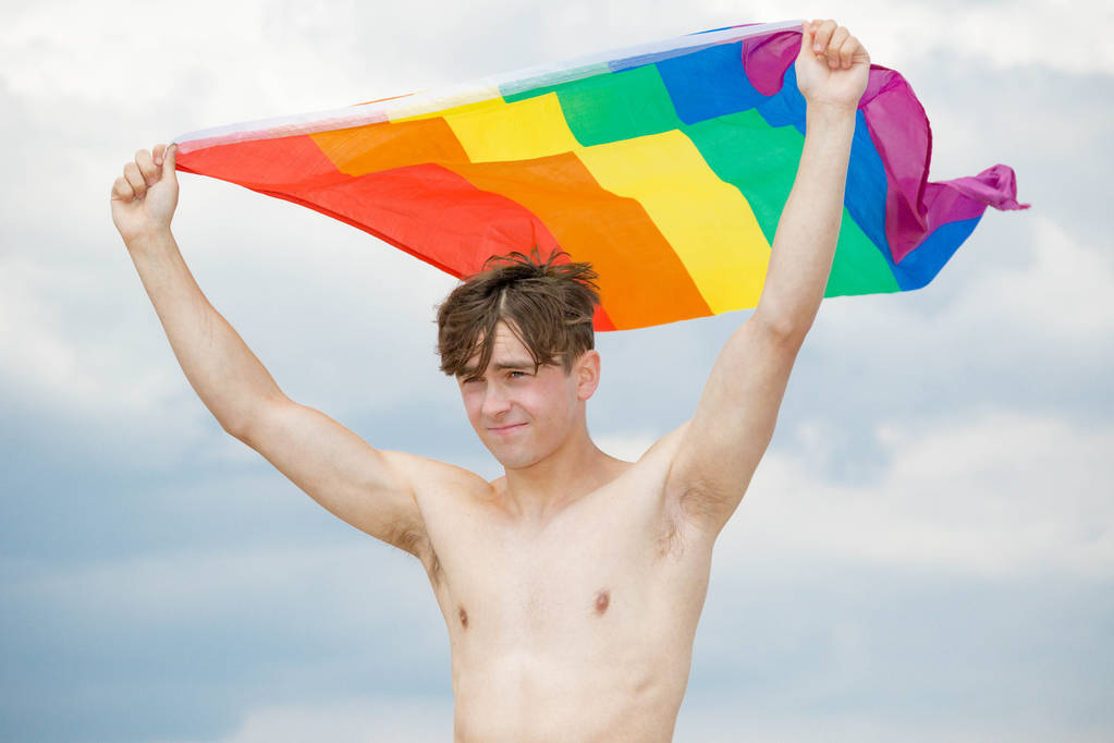 Blanc mâle sur une plage tenant un drapeau de fierté
 - Photo, image