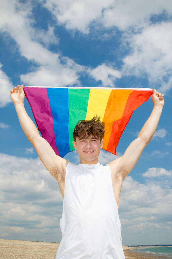 Valkoihoinen mies rannalla Ylpeys lippu kädessä
 - Valokuva, kuva