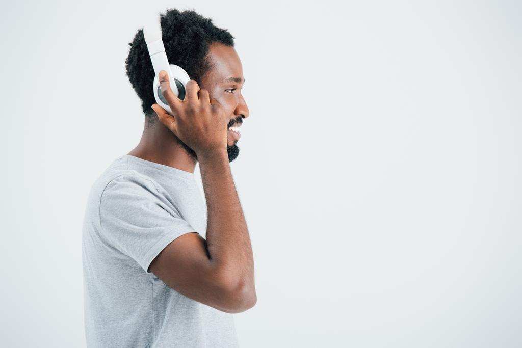 усміхнений афроамериканський чоловік слухає музику з навушниками, ізольований на сірому
 - Фото, зображення