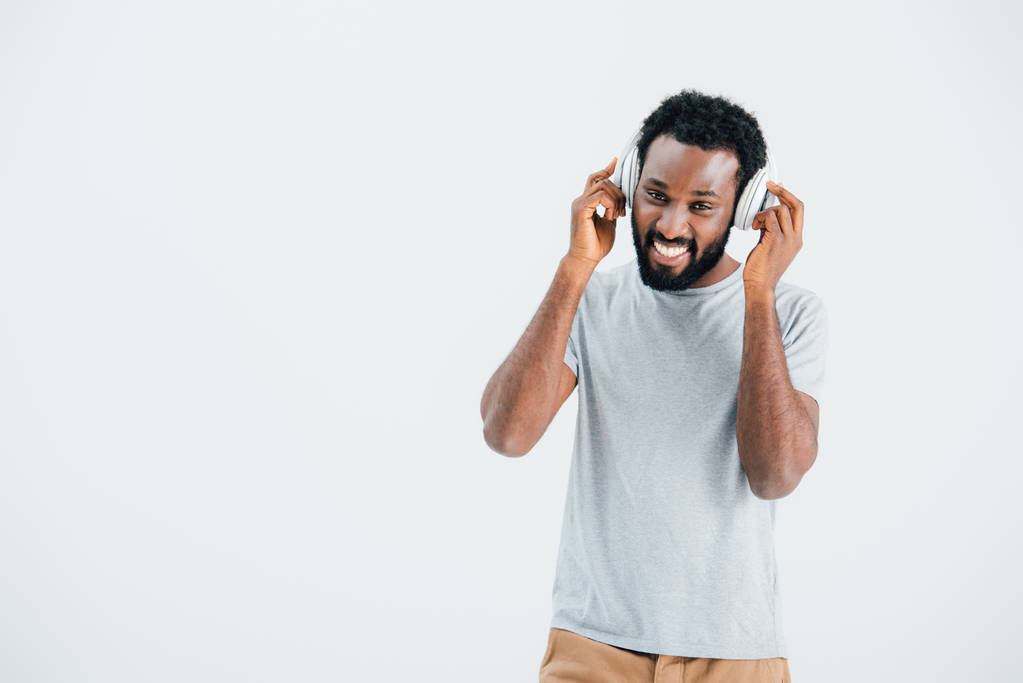 Veselý africký Američan poslouchá hudbu se sluchátky, izolované na šedé - Fotografie, Obrázek