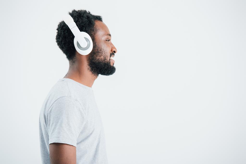 szczęśliwy African American Man słuchanie muzyki ze słuchawkami, izolowane na szarym - Zdjęcie, obraz