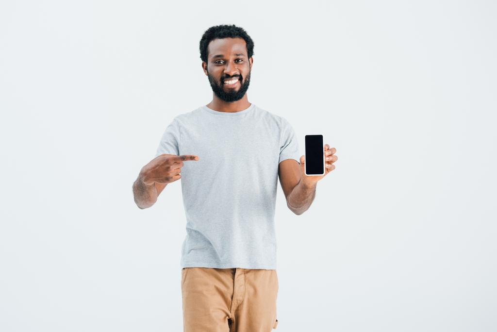 χαμογελαστός Αφρικανός Αμερικανός που δείχνει στο smartphone, απομονώνεται σε γκρι - Φωτογραφία, εικόνα