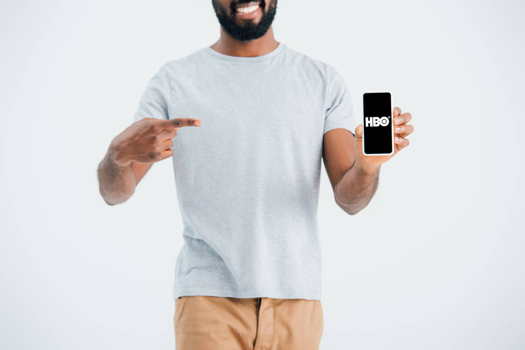 Київ, Україна-17 травня 2019: обрізаний вид афроамериканського людини вказуючи на смартфон з додатком HBO, ізольований по сірому  - Фото, зображення
