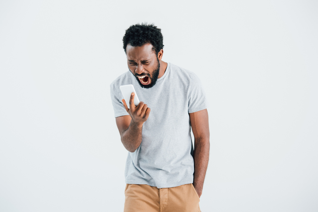 agresywny African American Man krzycząc i za pomocą smartfona, izolowane na szarym - Zdjęcie, obraz