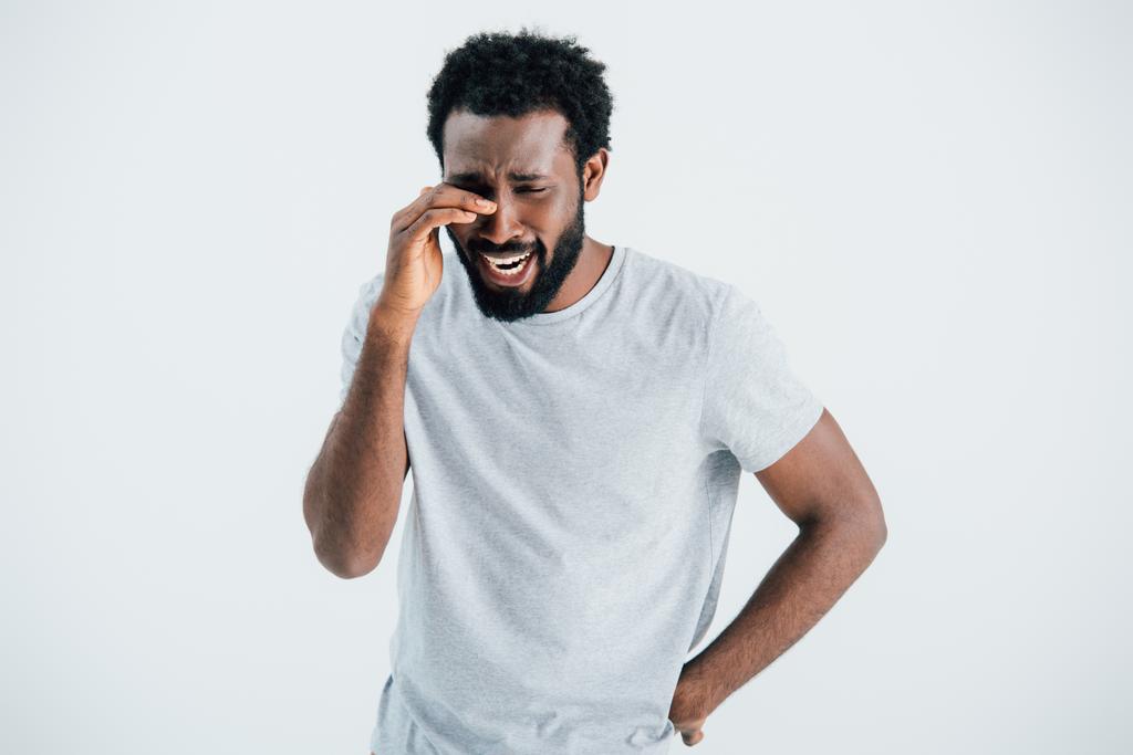 Aufgebrachter afrikanisch-amerikanischer Mann in grauem T-Shirt weint isoliert auf grau - Foto, Bild