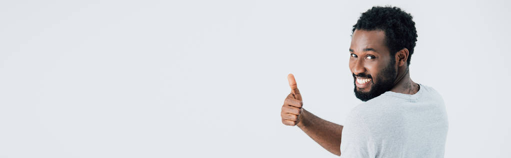 wesoły African American Man w szarym t-shirt pokazując kciuk w górę na szaro - Zdjęcie, obraz