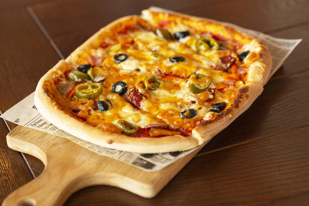 Pizza con peperoncini jalapeno e olive su tagliere di legno, attenzione selettiva
. - Foto, immagini