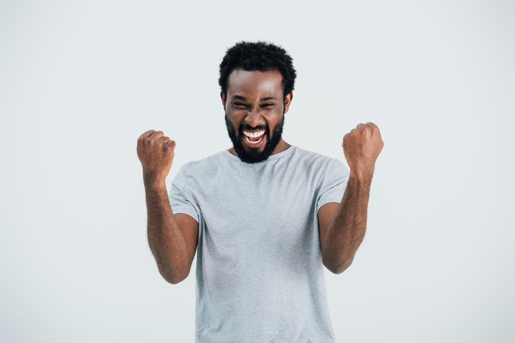 vzrušený afroamerický muž v šedé trikové košili, který je izolovaný na šedé - Fotografie, Obrázek