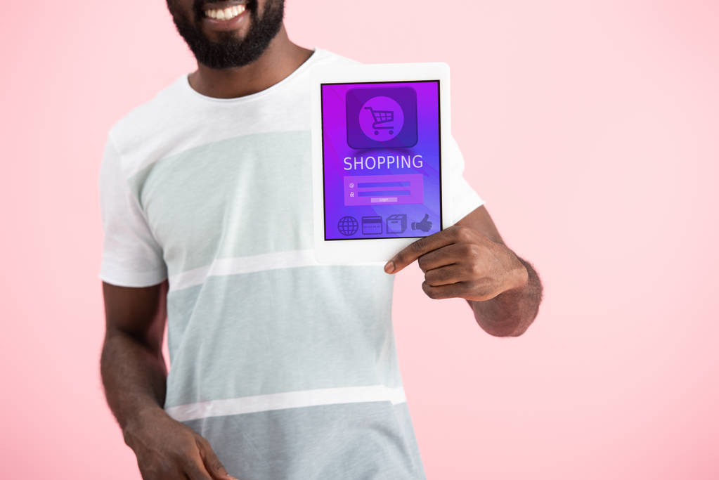 pembe izole alışveriş uygulaması ile dijital tablet gösteren gülümseyen afrikalı amerikalı adam kırpılmış görünümü - Fotoğraf, Görsel