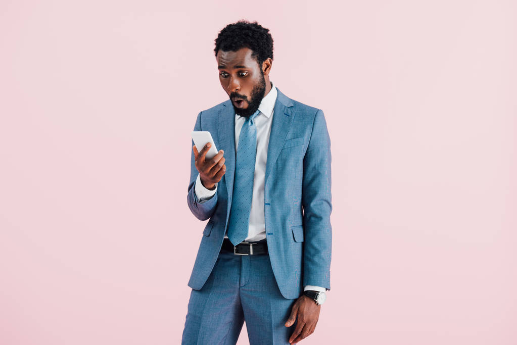 sorprendido hombre de negocios afroamericano usando teléfono inteligente, aislado en rosa
   - Foto, Imagen