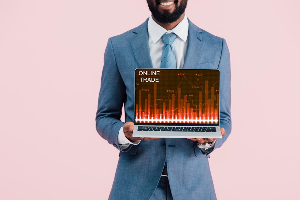 περικομμένη όψη του χαμογελαστή Αφρικανού Αμερικανού επιχειρηματία που δείχνει φορητό υπολογιστή με online εμπόριο απομονωμένη στο μπλε - Φωτογραφία, εικόνα