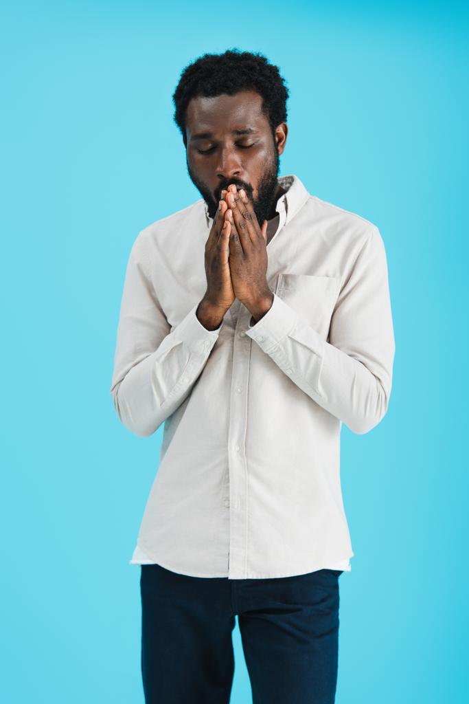 przystojny African American Man z zamkniętymi oczami modląc się na niebiesko - Zdjęcie, obraz