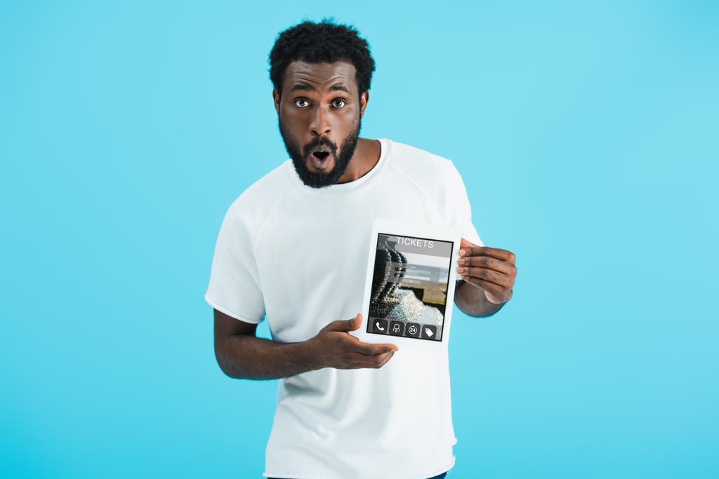 järkyttynyt afrikkalainen amerikkalainen mies näyttää digitaalinen tabletti liput app, eristetty sininen
 - Valokuva, kuva