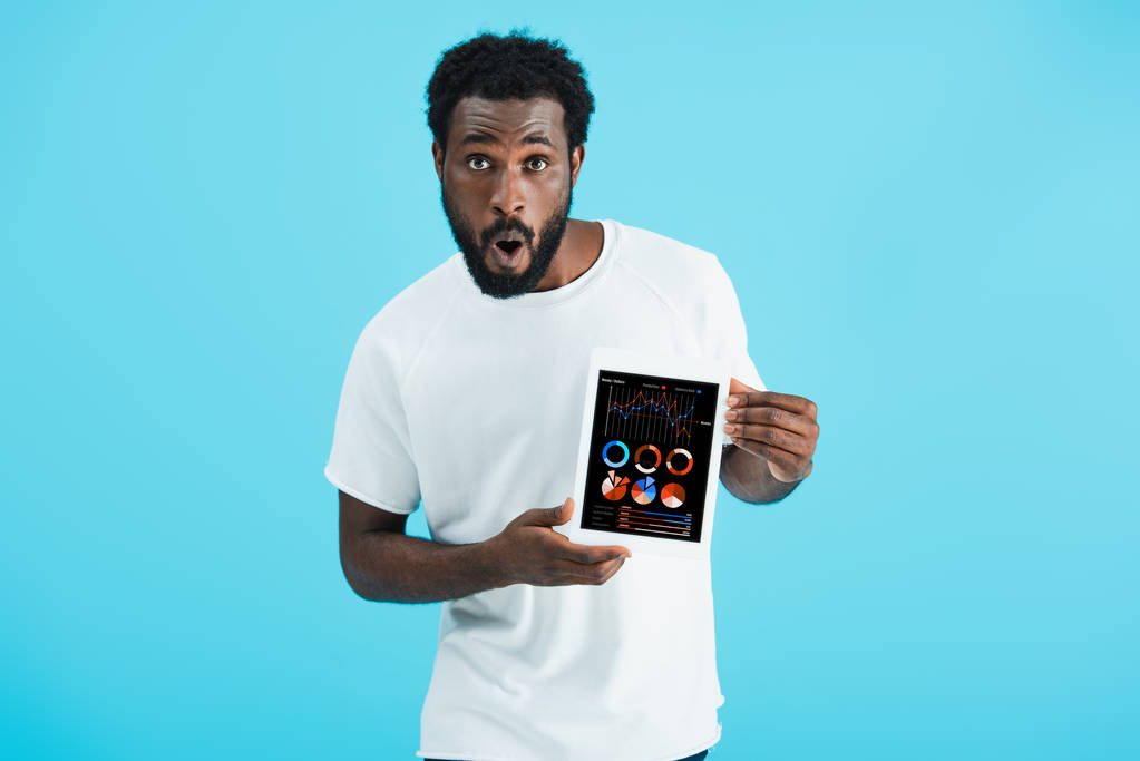 šokoval africký americký muž ukazující digitalizovaný tablet s infografickou aplikací, izolovaný na modrém - Fotografie, Obrázek