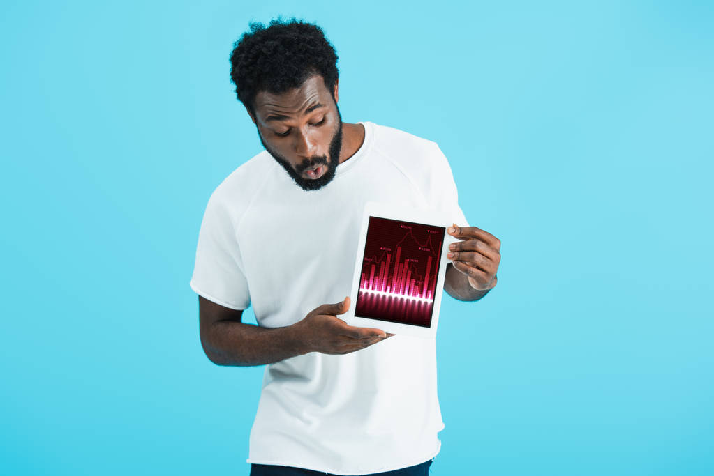 überrascht afrikanisch-amerikanischer Mann zeigt digitales Tablet mit Graphen-App, isoliert auf blau - Foto, Bild