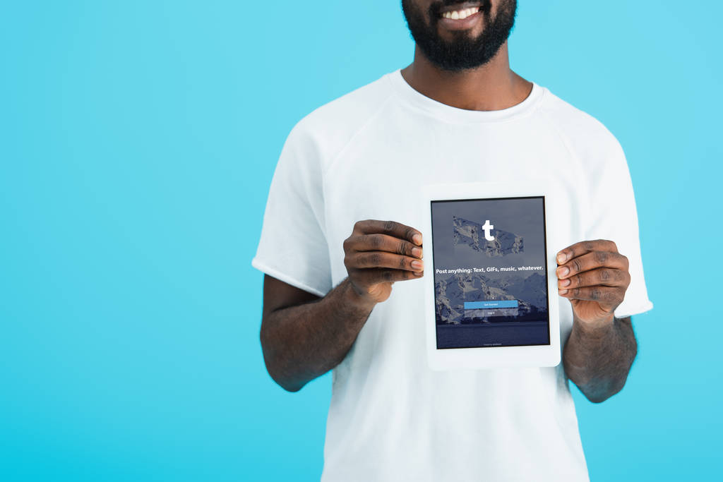 KYIV, UCRAINA - 17 MAGGIO 2019: vista ritagliata dell'uomo afroamericano che mostra tablet digitale con app tumblr, isolato su blu
 - Foto, immagini