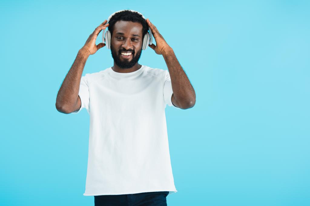 homme afro-américain souriant écoutant de la musique avec écouteurs, isolé sur bleu
 - Photo, image