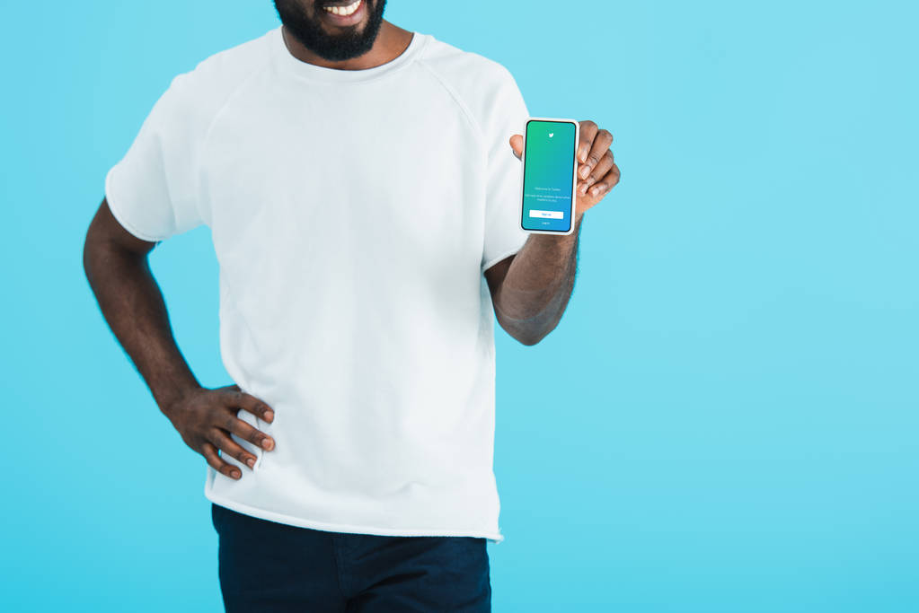 KYIV, UCRANIA - 17 de mayo de 2019: vista recortada del hombre afroamericano que muestra el teléfono inteligente con la aplicación de Twitter, aislado en azul
 - Foto, imagen