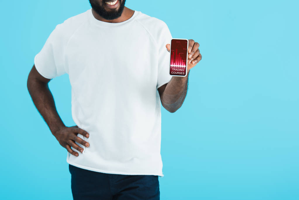 przycięte widok African American Man pokazując smartphone z kursów handlowych, izolowane na niebiesko - Zdjęcie, obraz