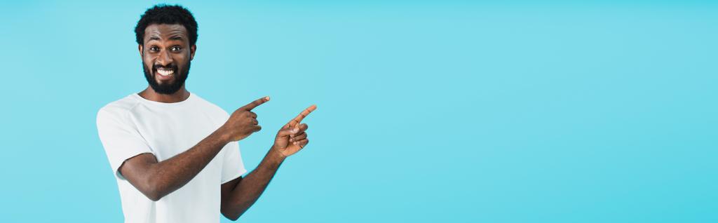 souriant homme afro-américain pointant isolé sur bleu
 - Photo, image