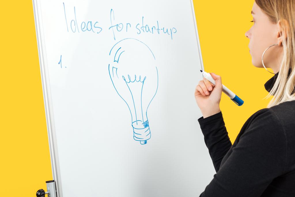 focada empresária de pé perto flipchart branco com espaço de cópia e lâmpada desenhada
 - Foto, Imagem