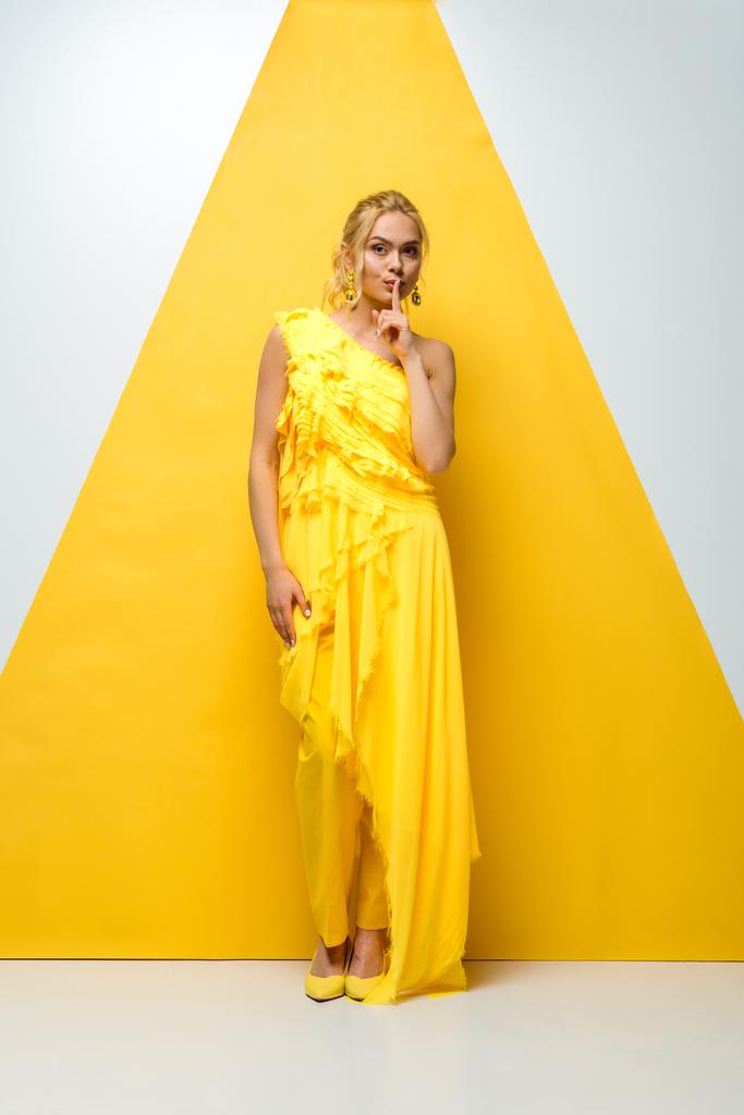 attrayant jeune femme regardant caméra et montrant signe de silence sur blanc et jaune
  - Photo, image