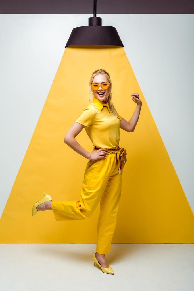 felice donna bionda in occhiali da sole in posa su bianco e giallo
  - Foto, immagini