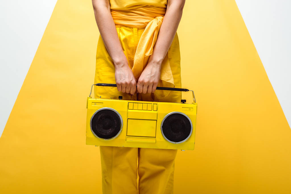 oříznutý pohled ženské pózace s retro boomboxu na bílém a žlutém  - Fotografie, Obrázek