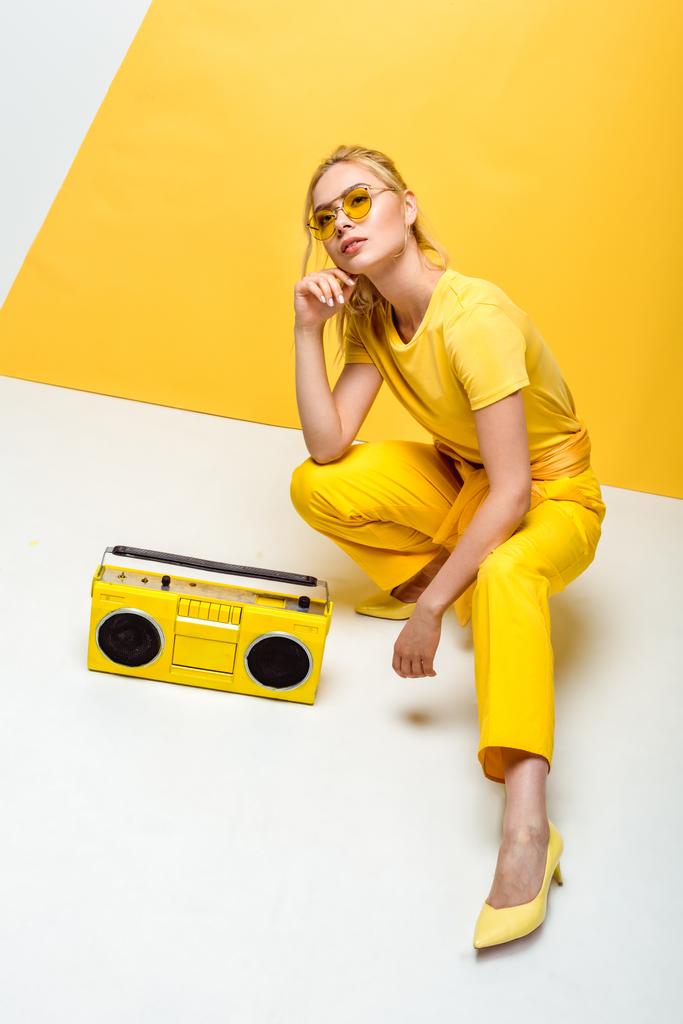 stijlvolle vrouw zittend in de buurt van retro Boombox op wit en geel  - Foto, afbeelding